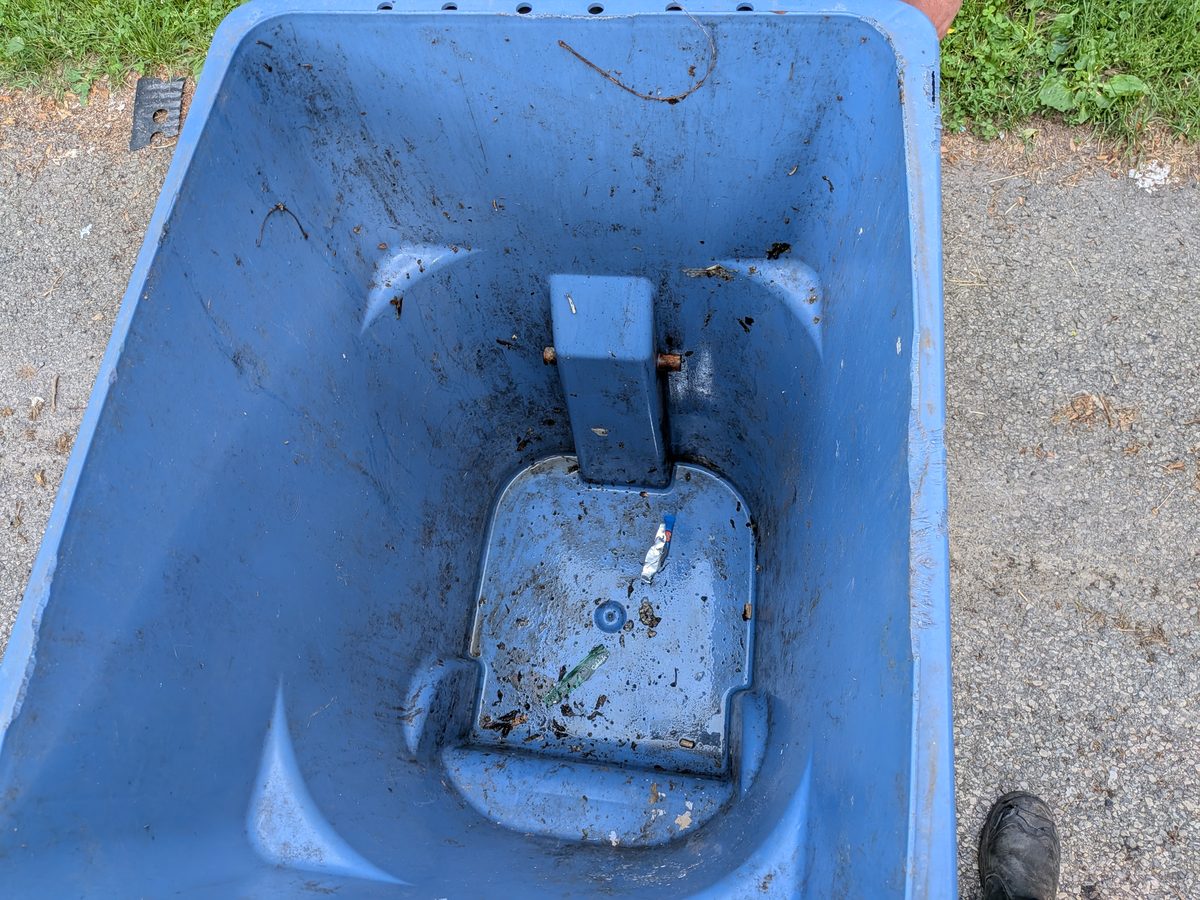 The inside of a wheeled bin, dirty and stuck with debris